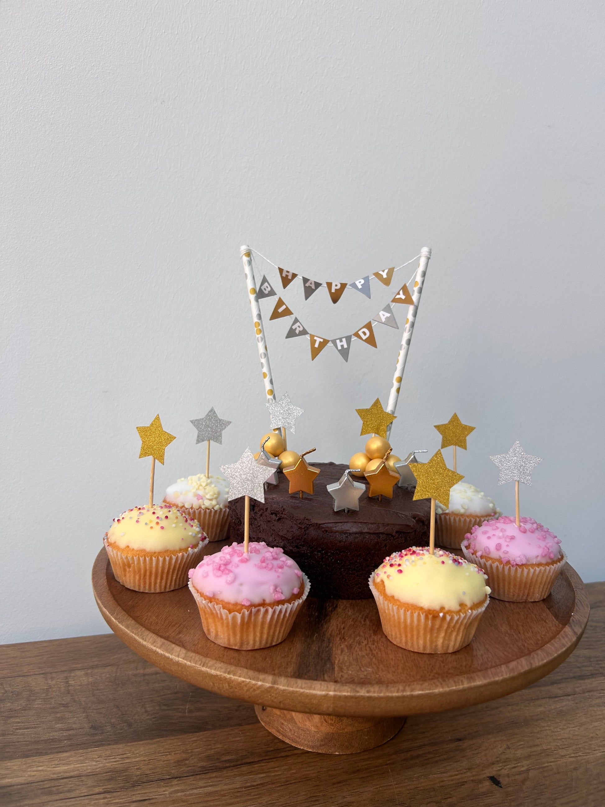 Wooden plate with cupcakes and decorative flags on a light gray background