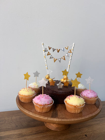 Wooden plate with cupcakes and decorative flags on a light gray background